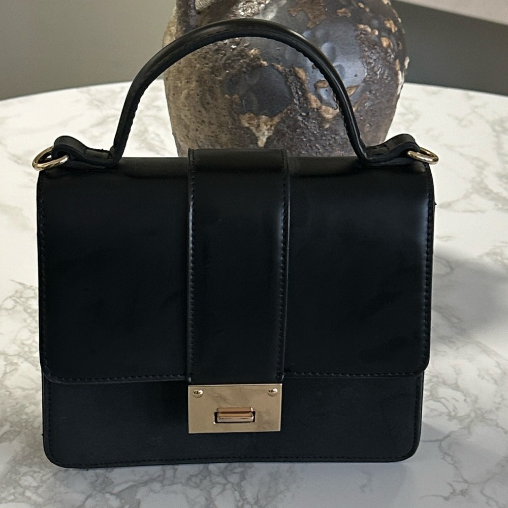 Chic, black, square-shaped purse with top handle, gold hardware, and a flip lock